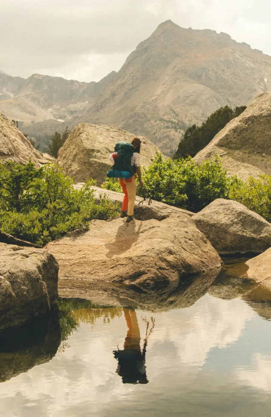 A backpacker pausing beside a mountain lake on a long journey